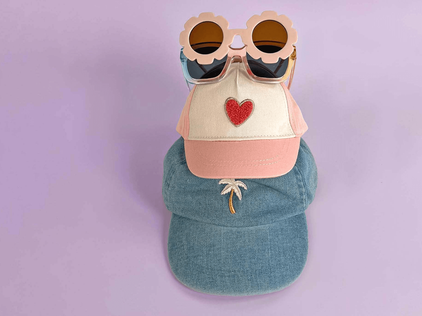 A playful arrangement of hats, including a cap with heart decorations, highlighting products from Orchestra