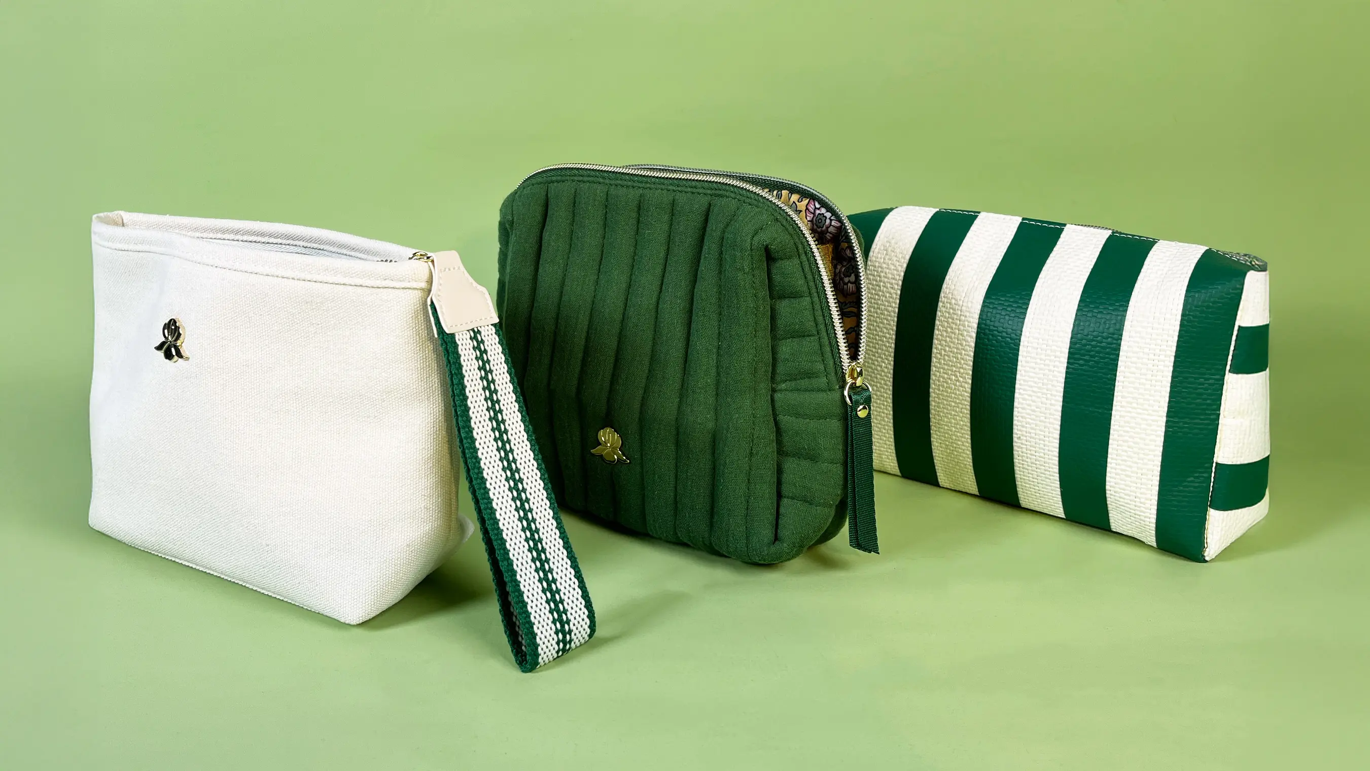 three green & white cosmetic bags in varied styles, representing Sisley's chic accessory collection.